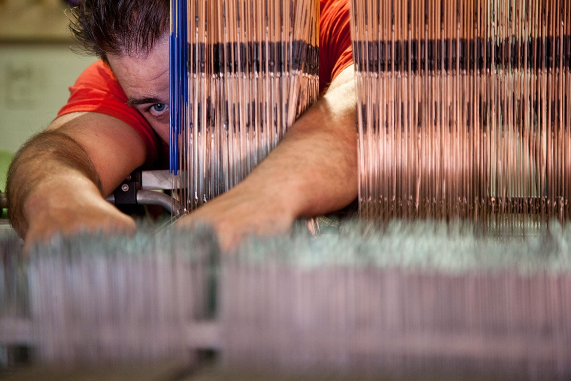 Photo of student reaching in textile loom.