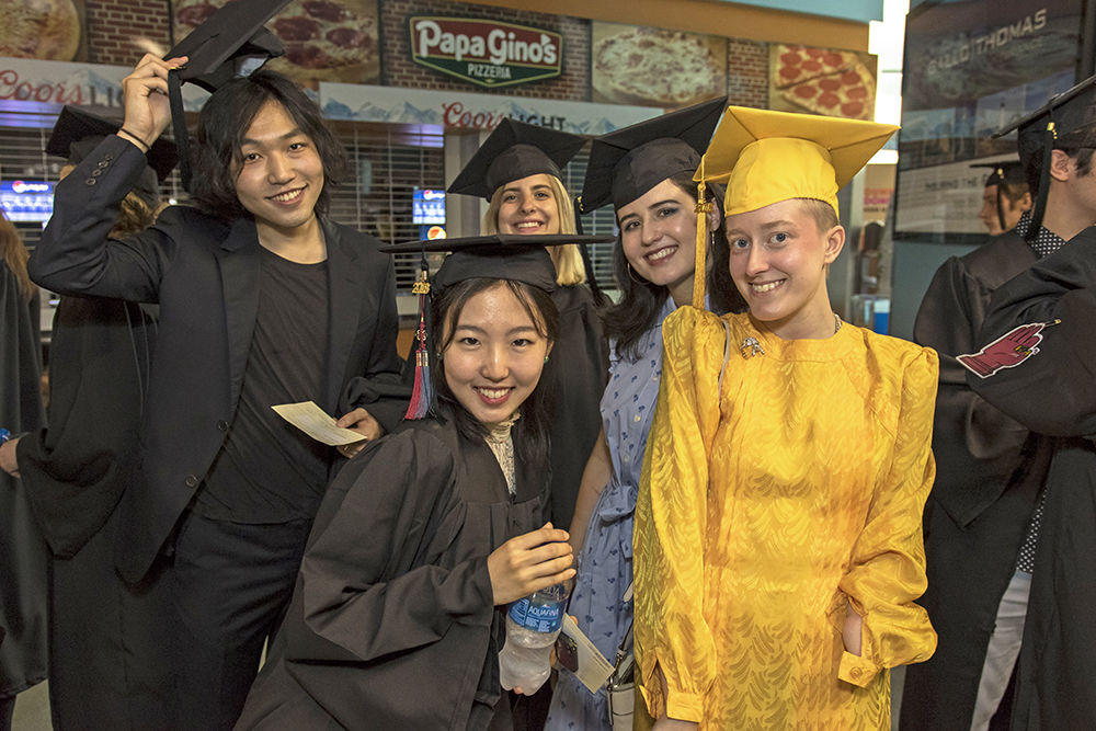 Group of students in caps and gowns - one student in all gold.