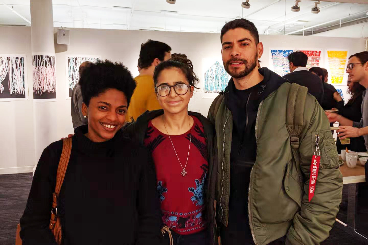 Photo of three alumni standing in a gallery space.