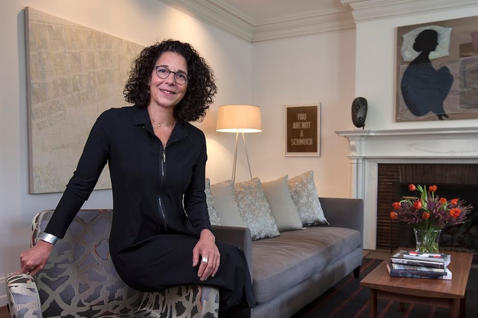 RISD President Rosanne Somerson sits on a grey couch.