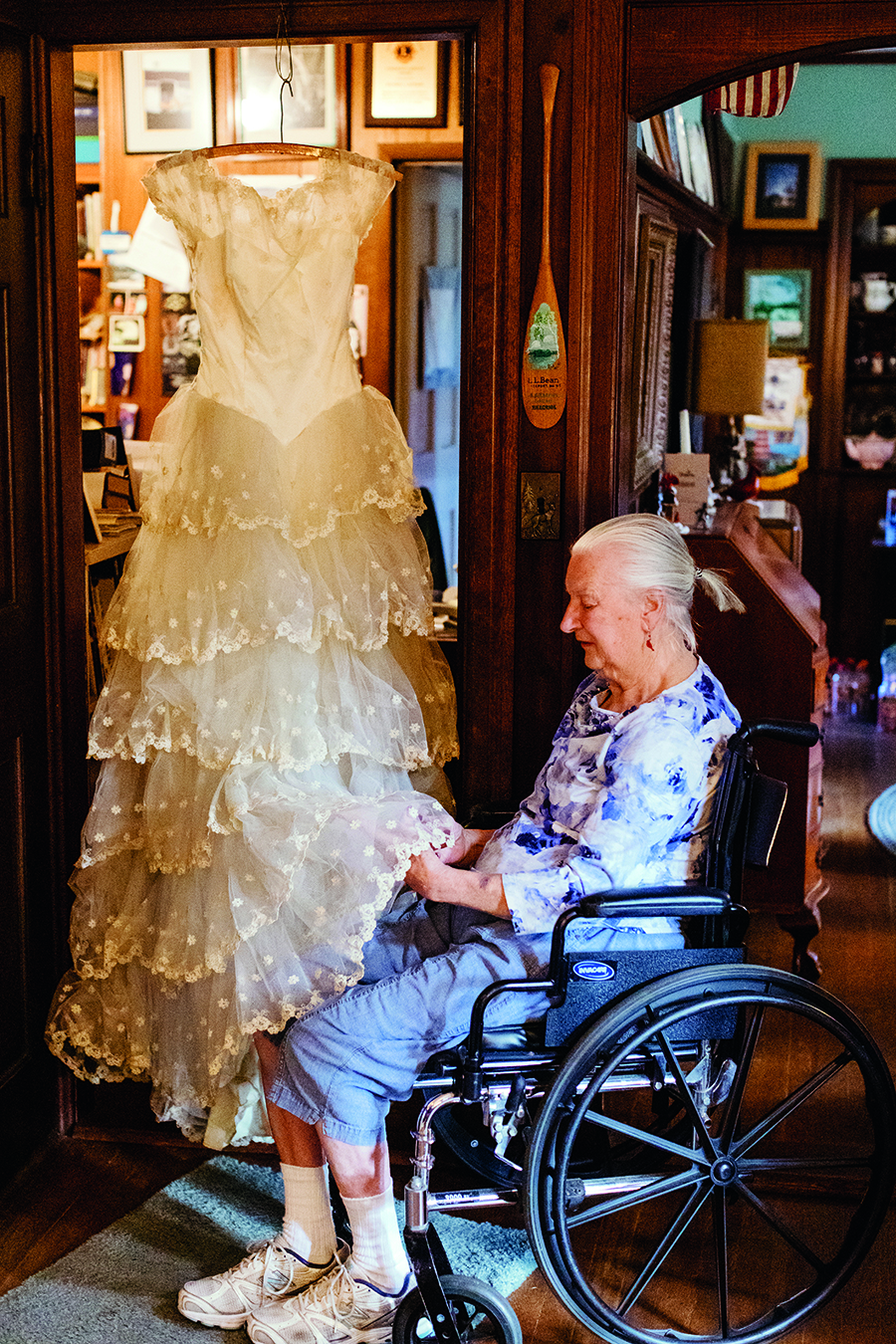 Woman in a wheelchair touching a white dress on a hanger