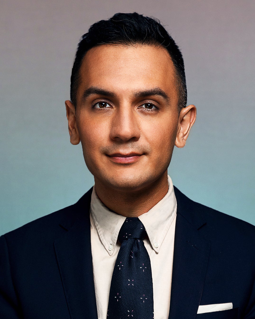 Image of a man in a black suit and tie with white shirt and pocket square