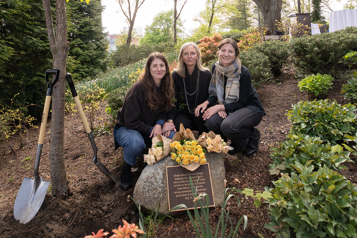 Lindsey Mayer-Beug 05 FAV, Cidney Vinall and Lauren Mayer-Beug 05 FAV crouch near the tree and plaque commemorating John Beug