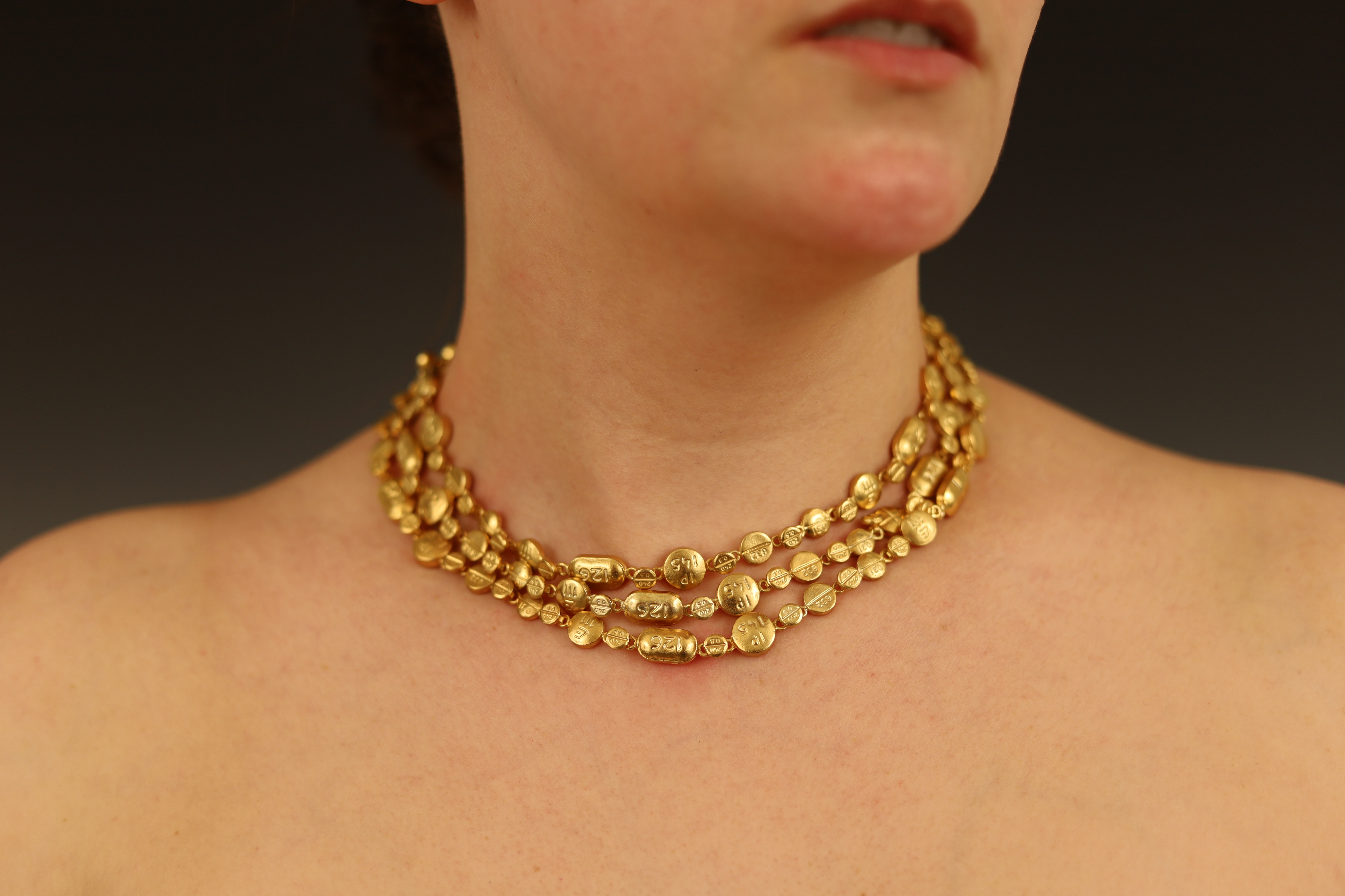 Image of a person's neck, wearing a gold chain necklace