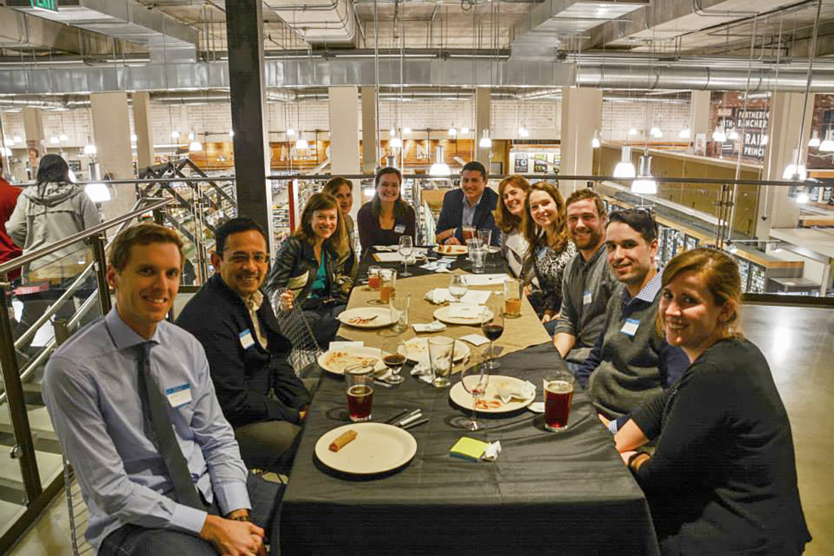 Photo of club members posing for the camera at a long table while enjoying dinner.