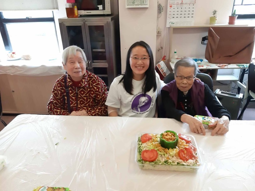 RISD alumna poses with two residents of the Yan Chai Hospital Care and Attention Home during the Club's #RISDServes project.