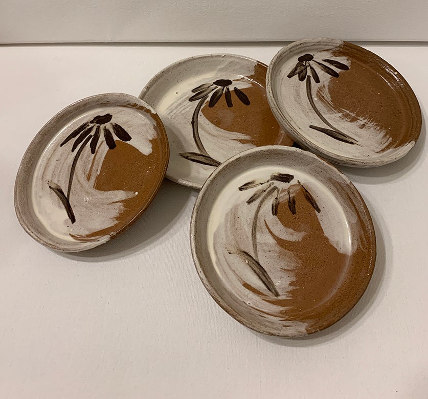 Photo of four plates with coneflowers on them. 