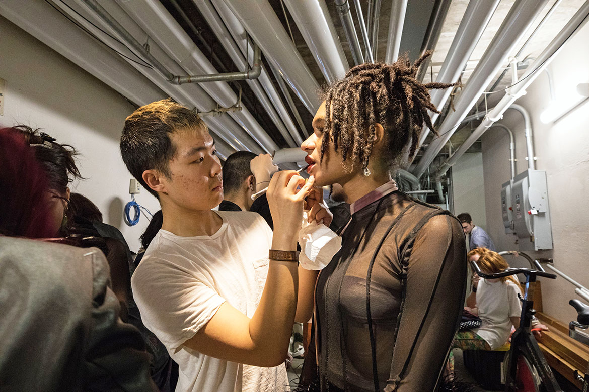 Photo of student applying lipstick to model at collection 2019