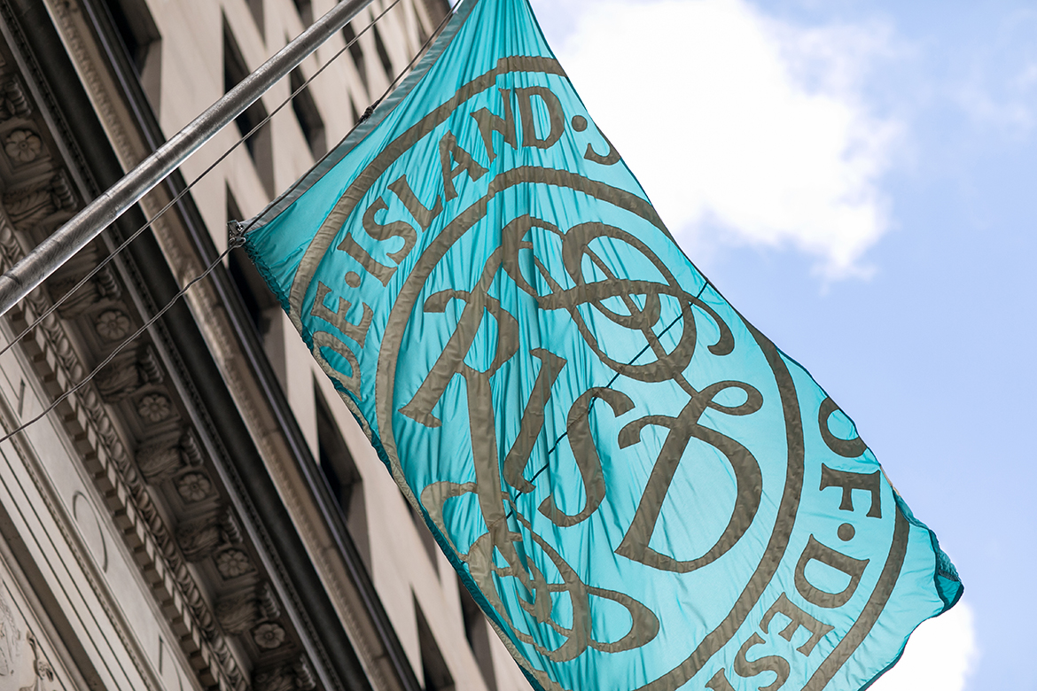 A RISD flag snaps in the breeze on a summer day. 