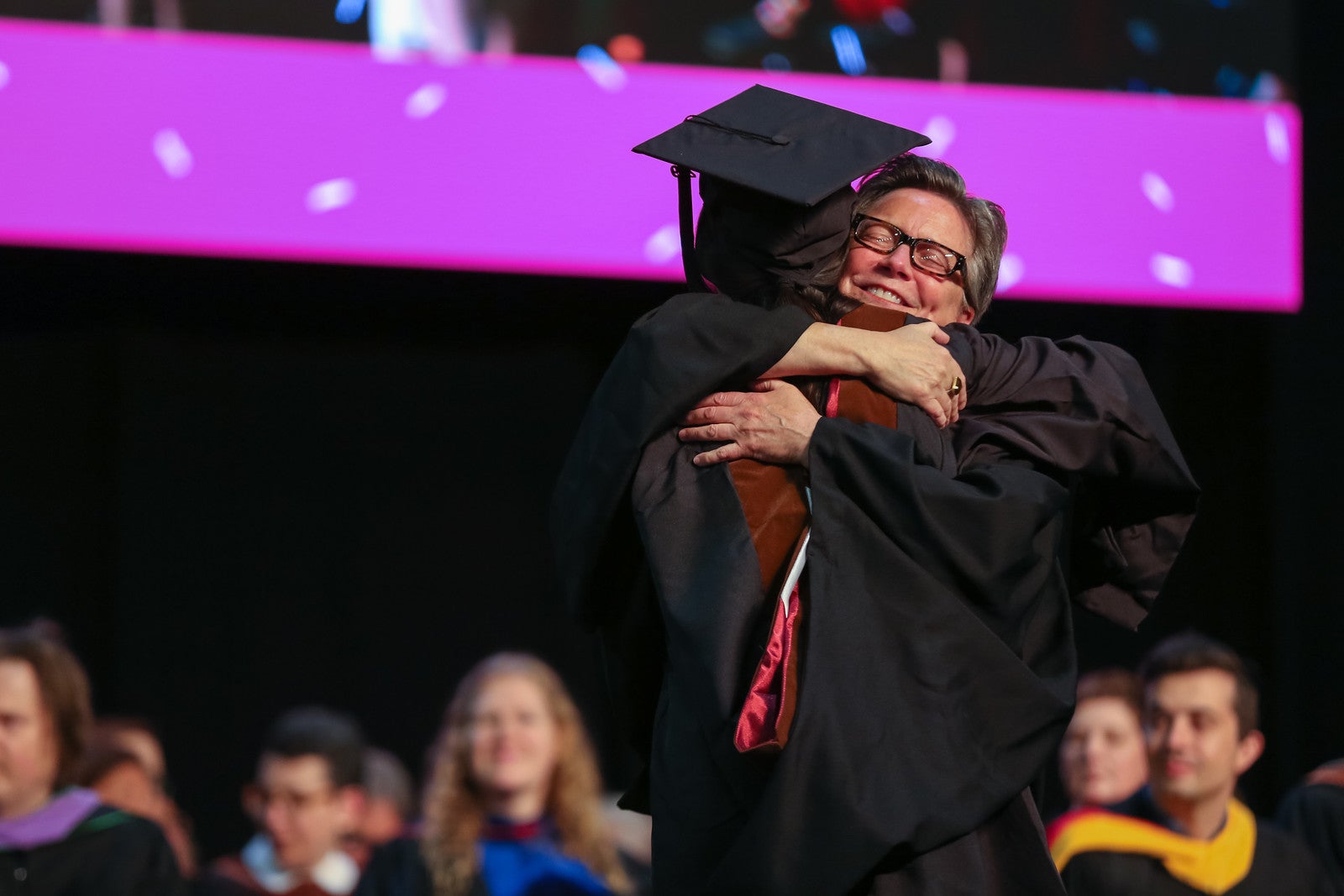 Photo of someone hugging a graduating student at Commencement