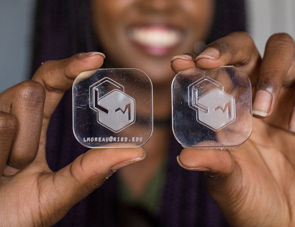 Photo of Lindsey Moreau holding up her clear plastic business cards she designed.
