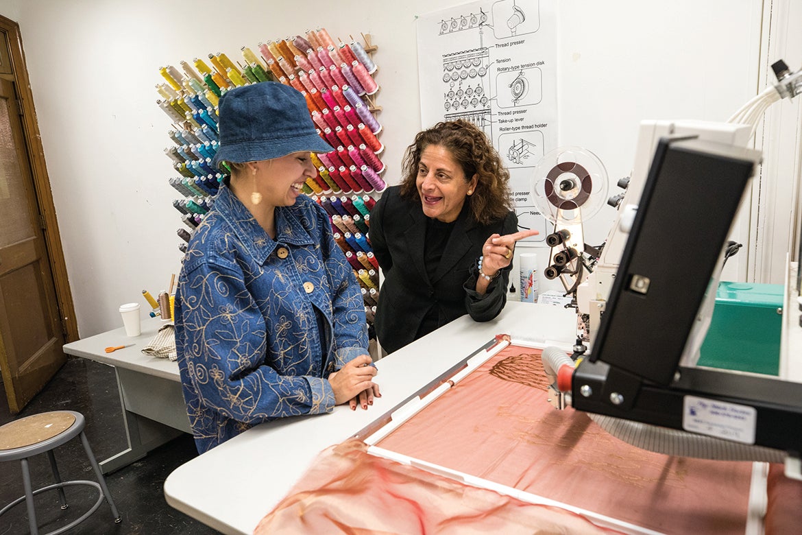 Photo of Anais Missakian speaking with a student in the Textiles studio