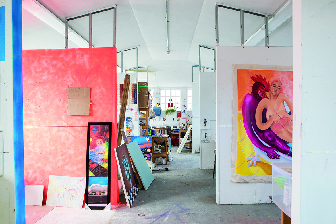 Photo of a painting studio with lots of paintings and materials throughout the space