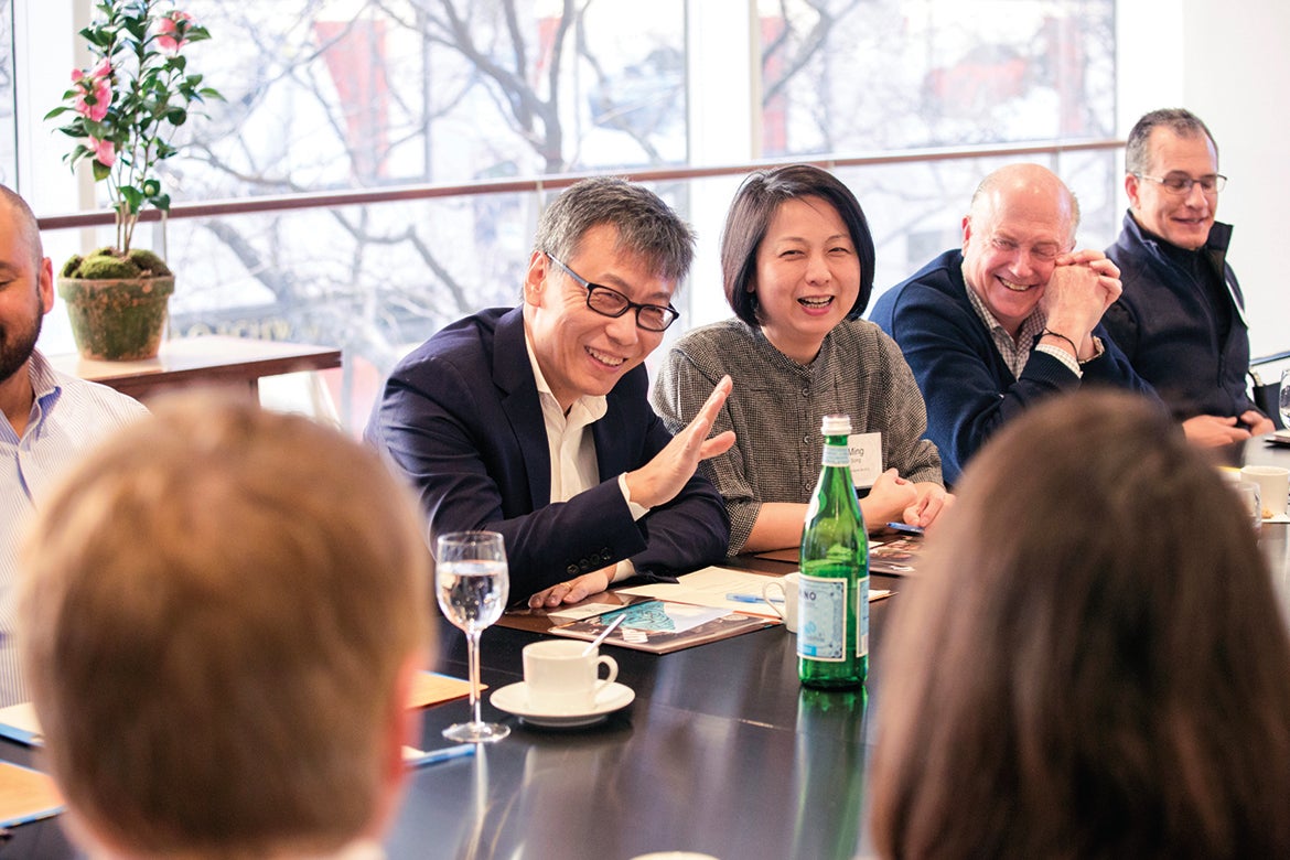 Photo of Shanming Shi and Ming Song sitting at a table with others in conversation