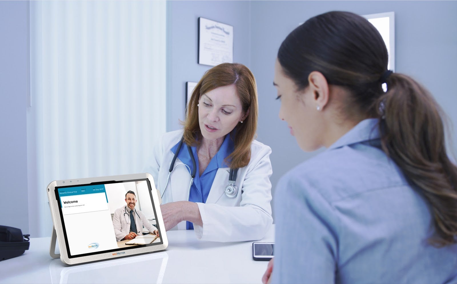 A patient speaking with a doctor who is referring to a tablet screen.