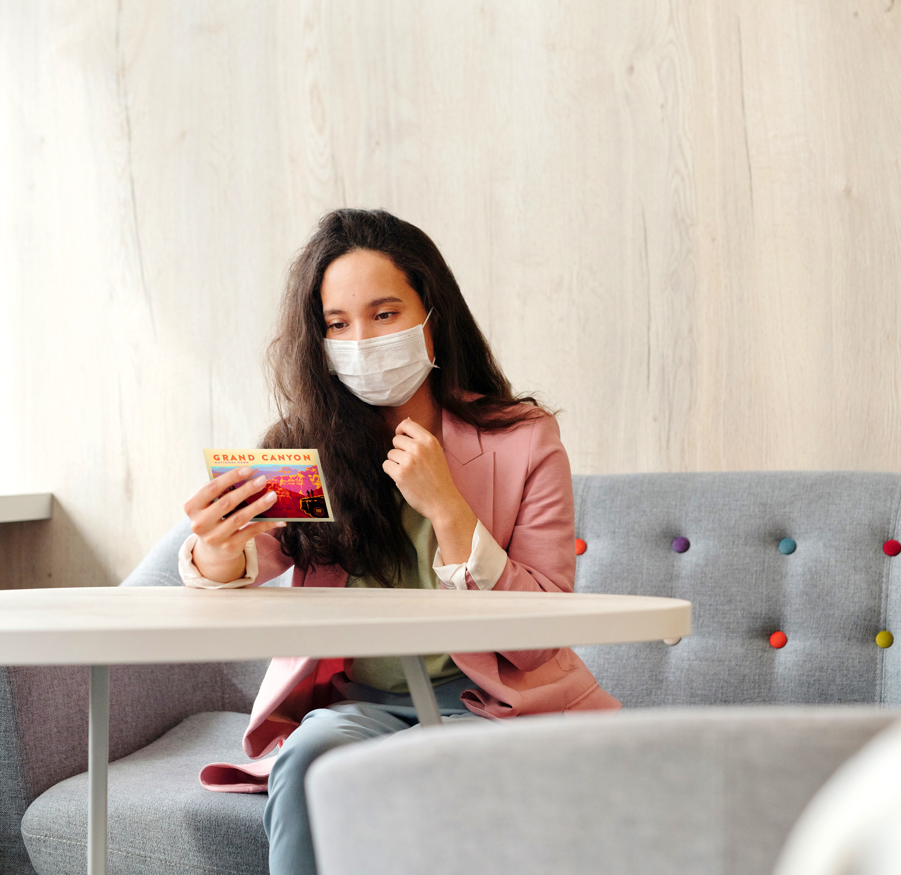 A woman in a mask reading a postcard.