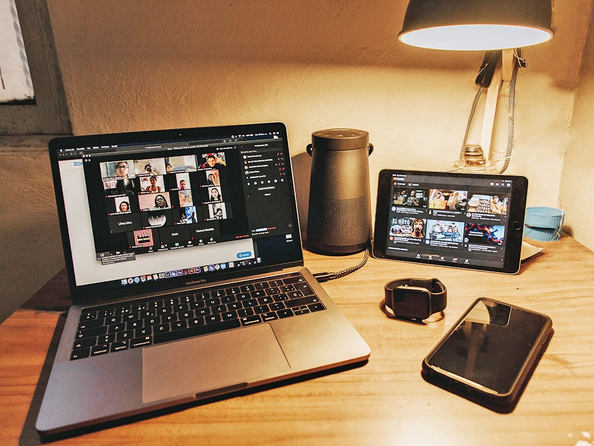 Photo of multiple devises showing Zoom on a desk.