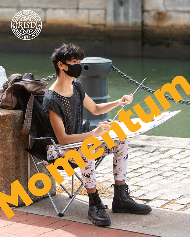 The cover of the Fall 2020 issue of Momentum magazine, featuring a student working on an art project wearing a mask, sitting by the Providence River.