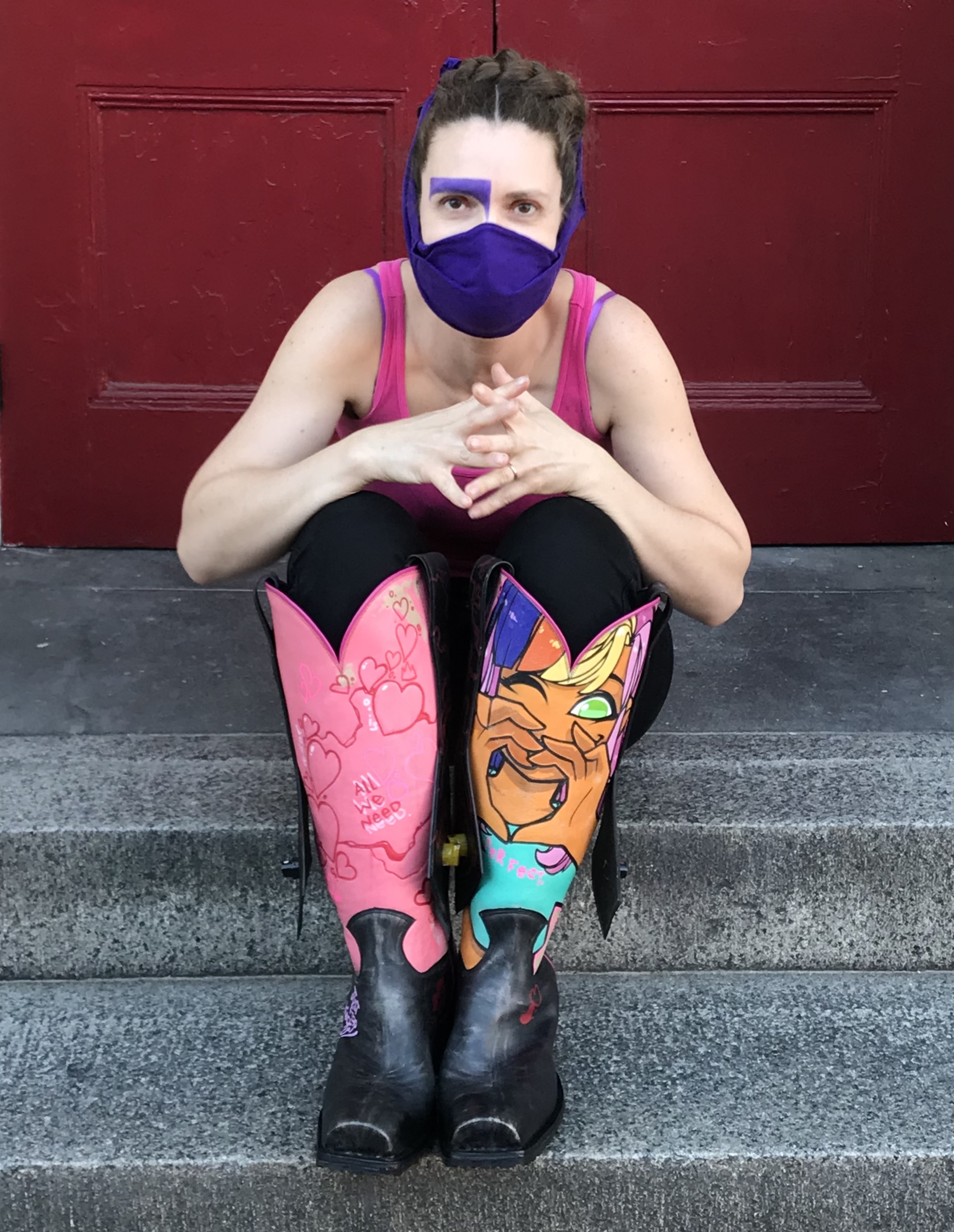 RISD Alumni Sarah Guerin sitting on cement stairs wearing colorful boots and a blue face mask.
