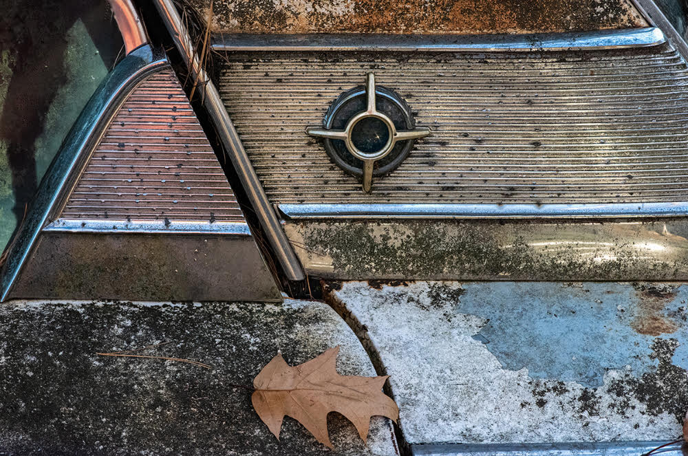 Side detail view of a deteriorating classic car