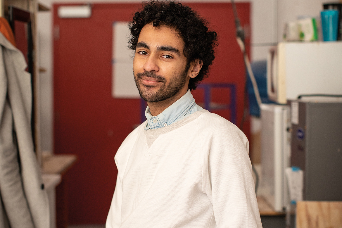 Image of a male in a white sweater and white collared shirt 