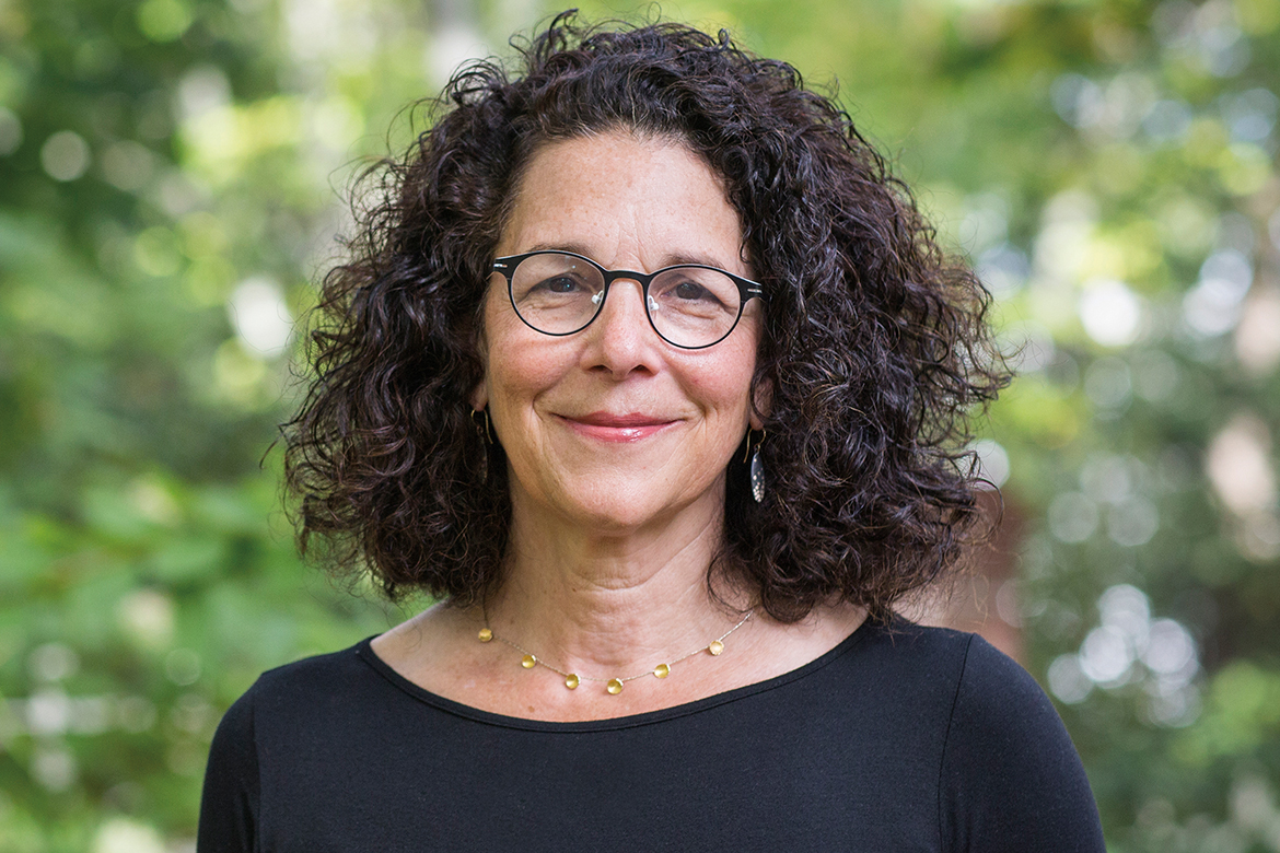 A headshot of Rosanne Somerson, RISD's President, in front of a blurred background of green trees.