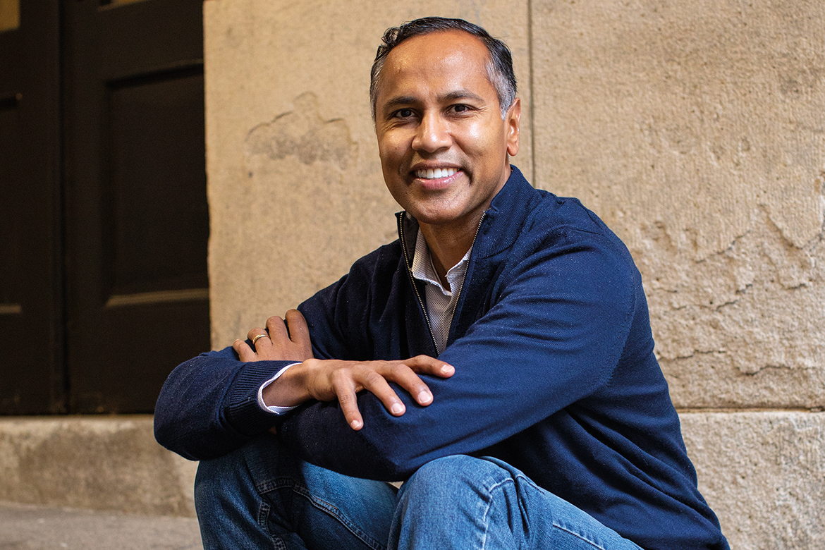 Image of a seated male in a blue zip front sweater and jeans