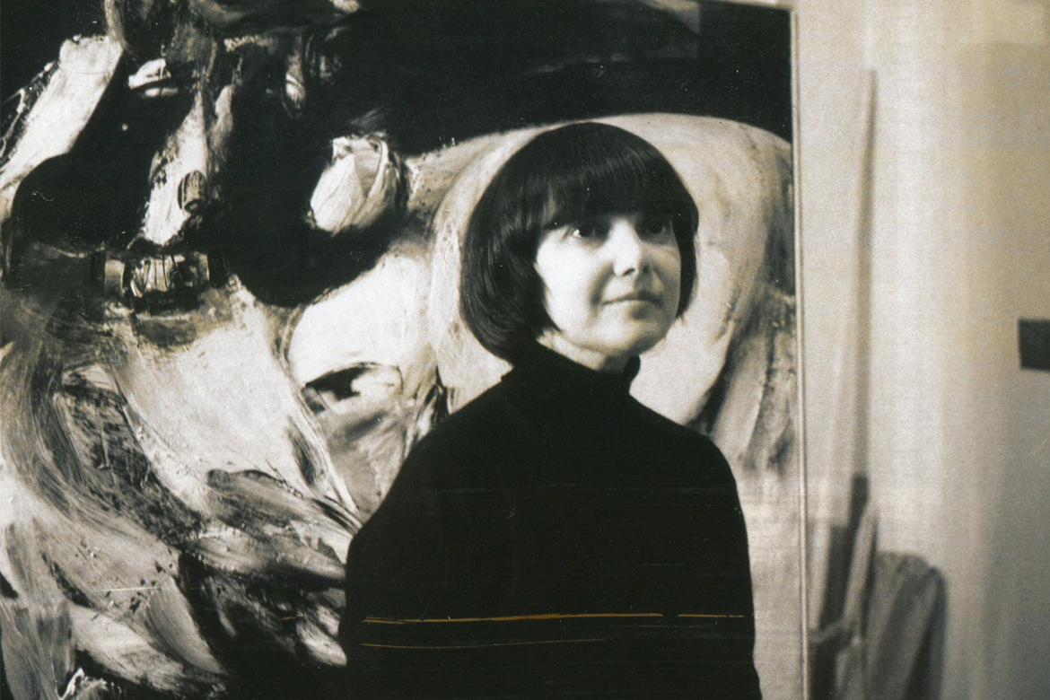 Black & White image of a woman with short dark hair in front of a painting 