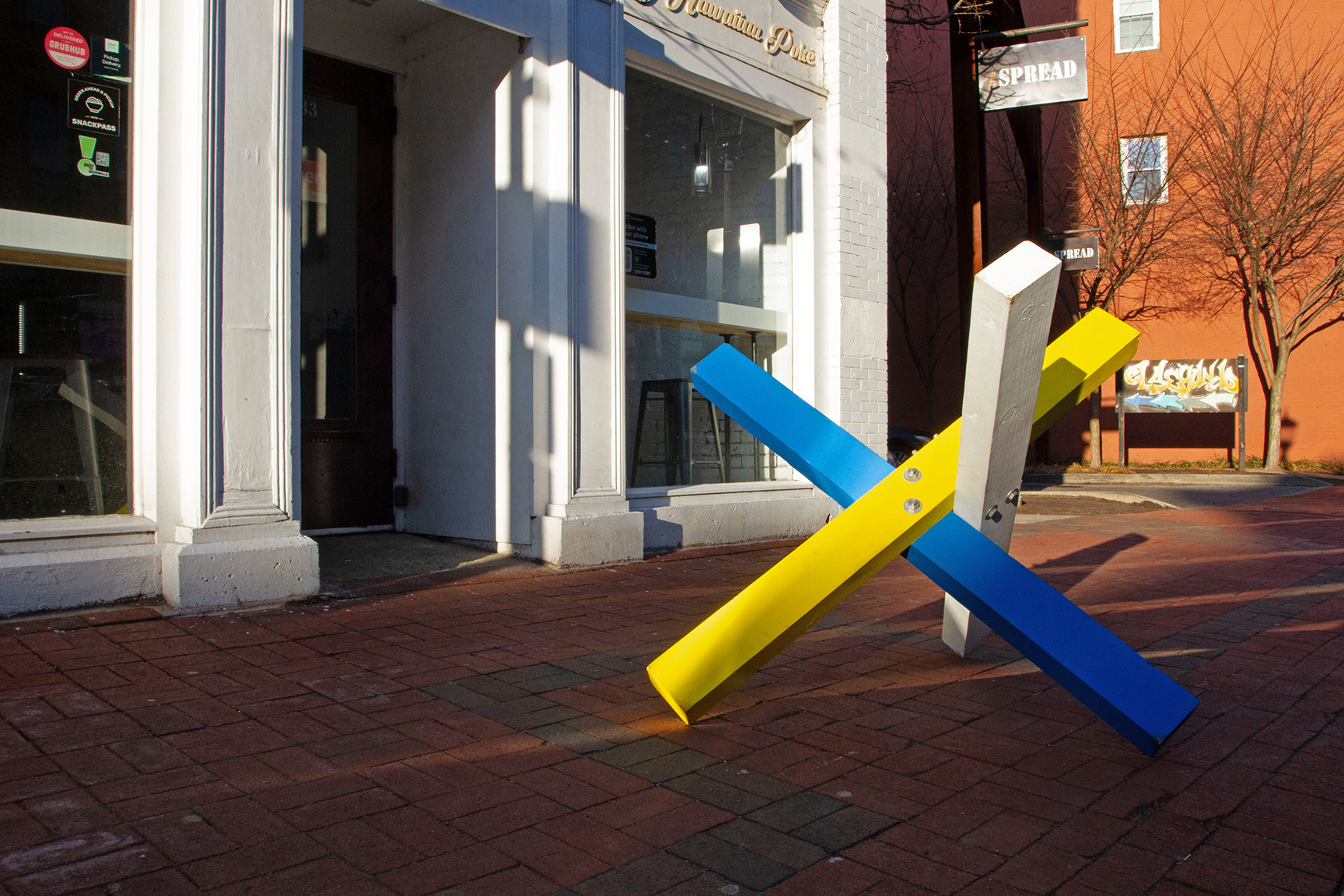 A blue, yellow and white structure in front of a building