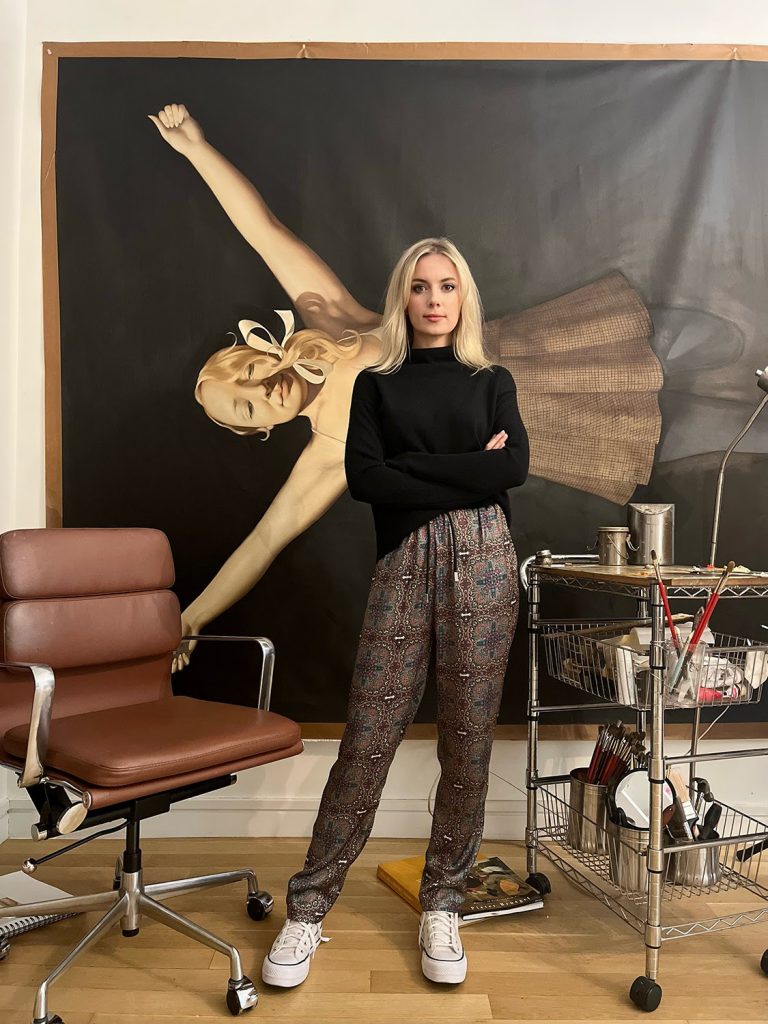 Anna Weyant standing in front of a painting at her studio