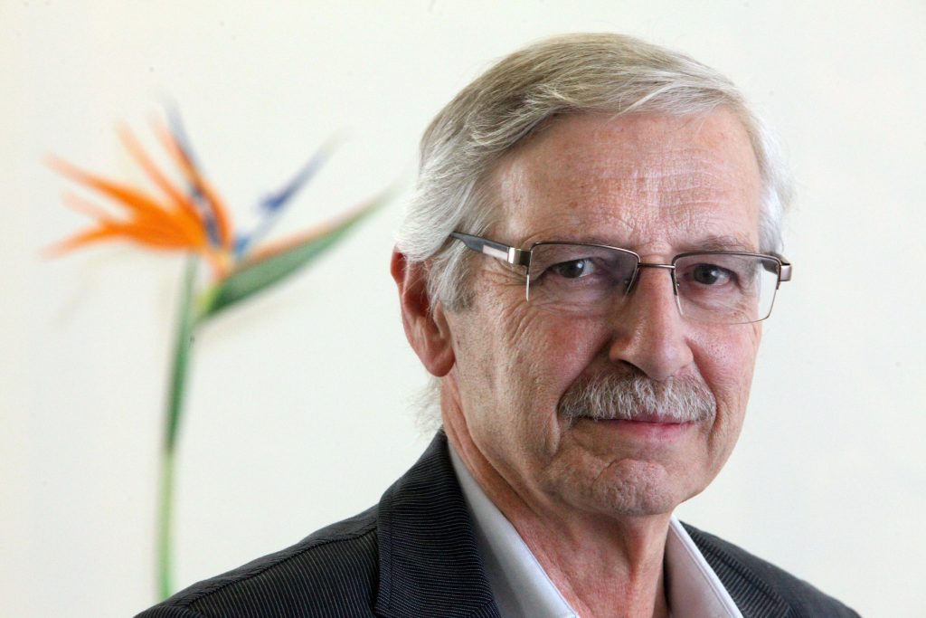 A portrait of Santiago Cárdenas standing in front of an orange flower