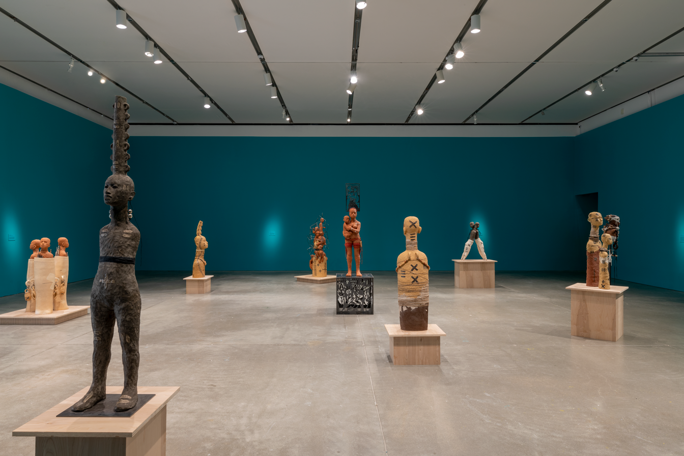 A collection of clay human sculptures in an exhibition hall