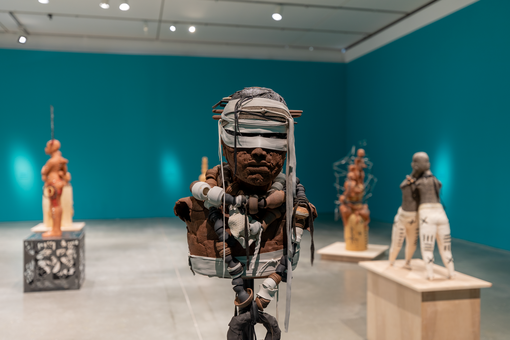 A brown clay bust with fabric sash wound around his head