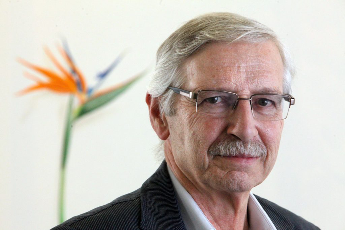 A portrait of Santiago Cárdenas standing in front of an orange flower