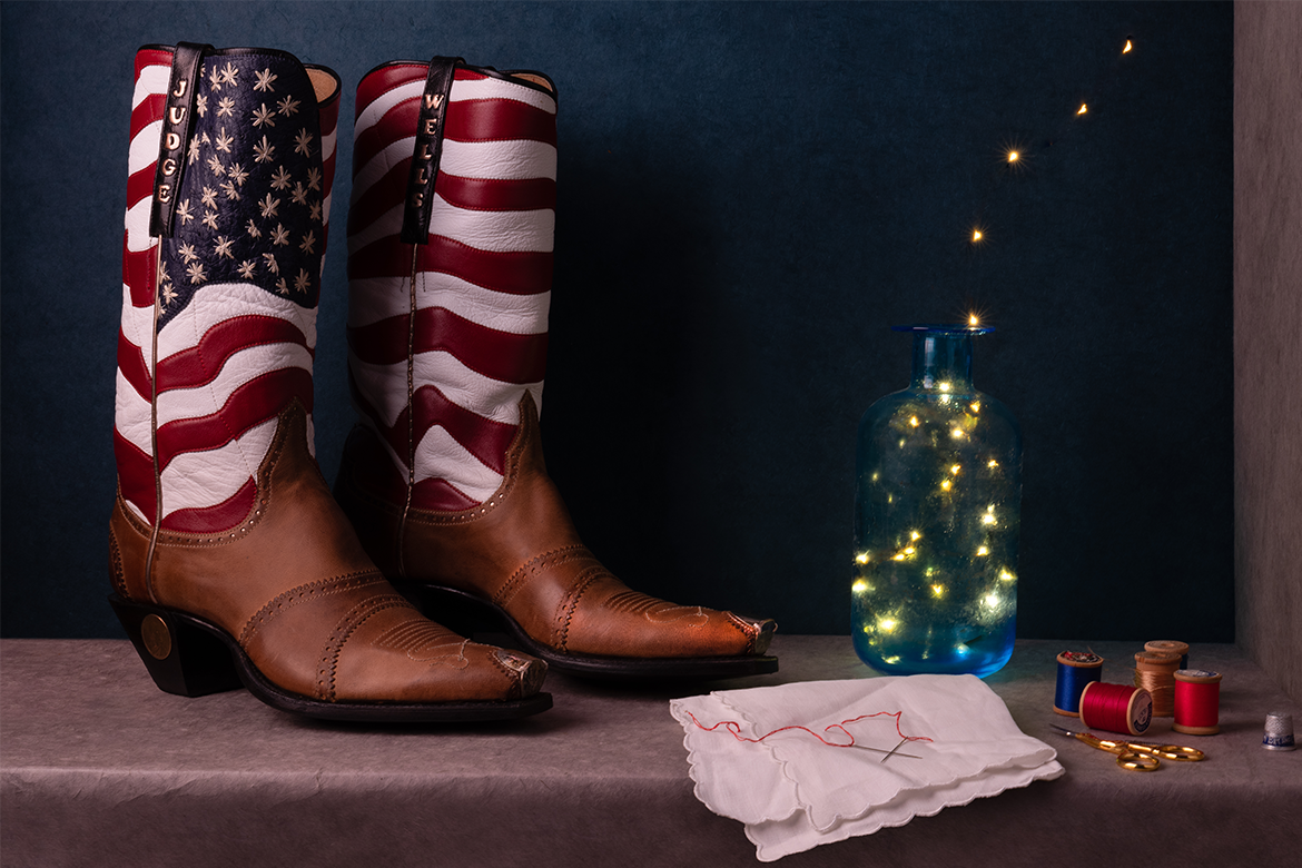 A pair of boots with a print of the American flag beside a jar of lights and sewing supplies