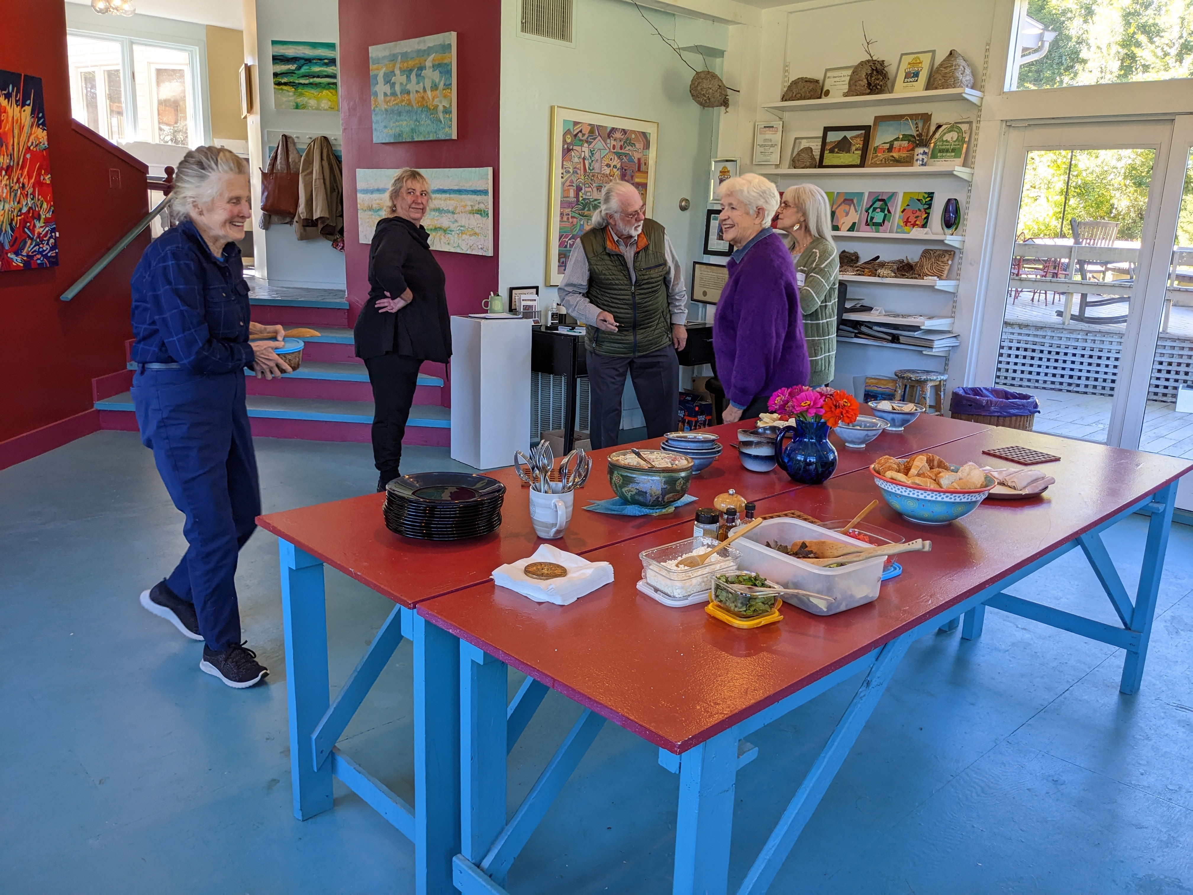 Five people chatting and smiling beside a table of food in a gallery