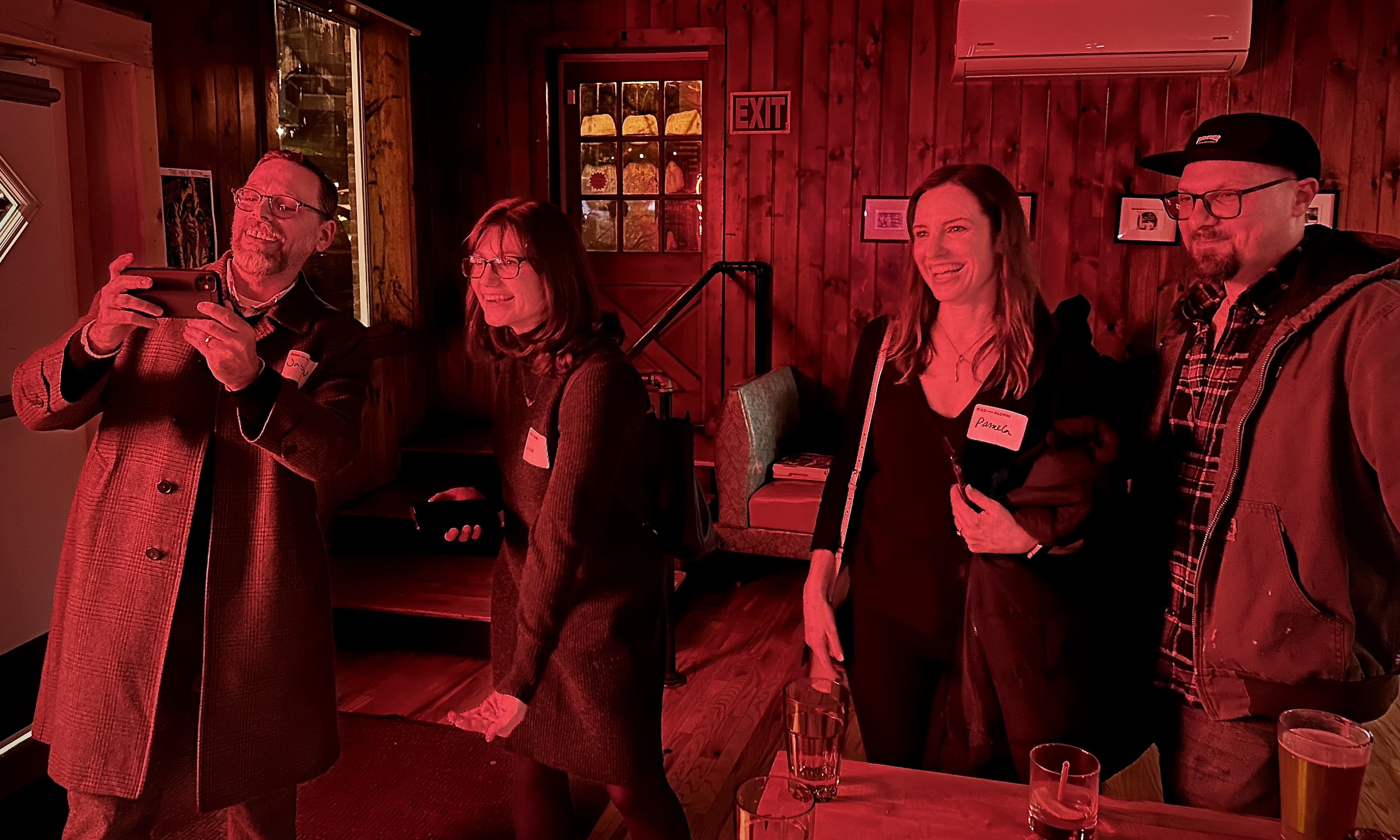 Four people standing in a bar and smiling at something off-camera