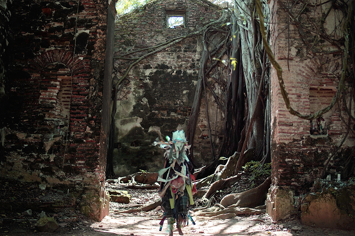 A person draped in fabrics and standing in front of a building