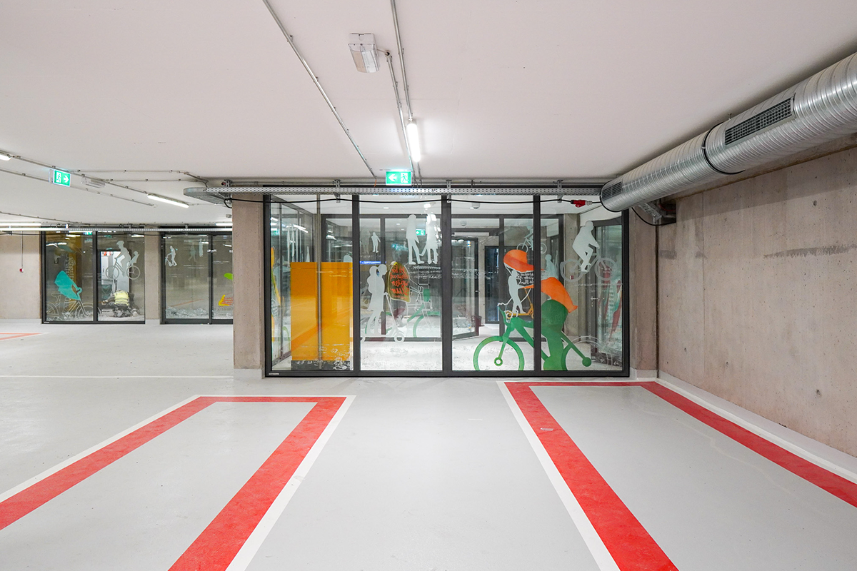 A glass enclosure decorated with graffiti in a parking garage