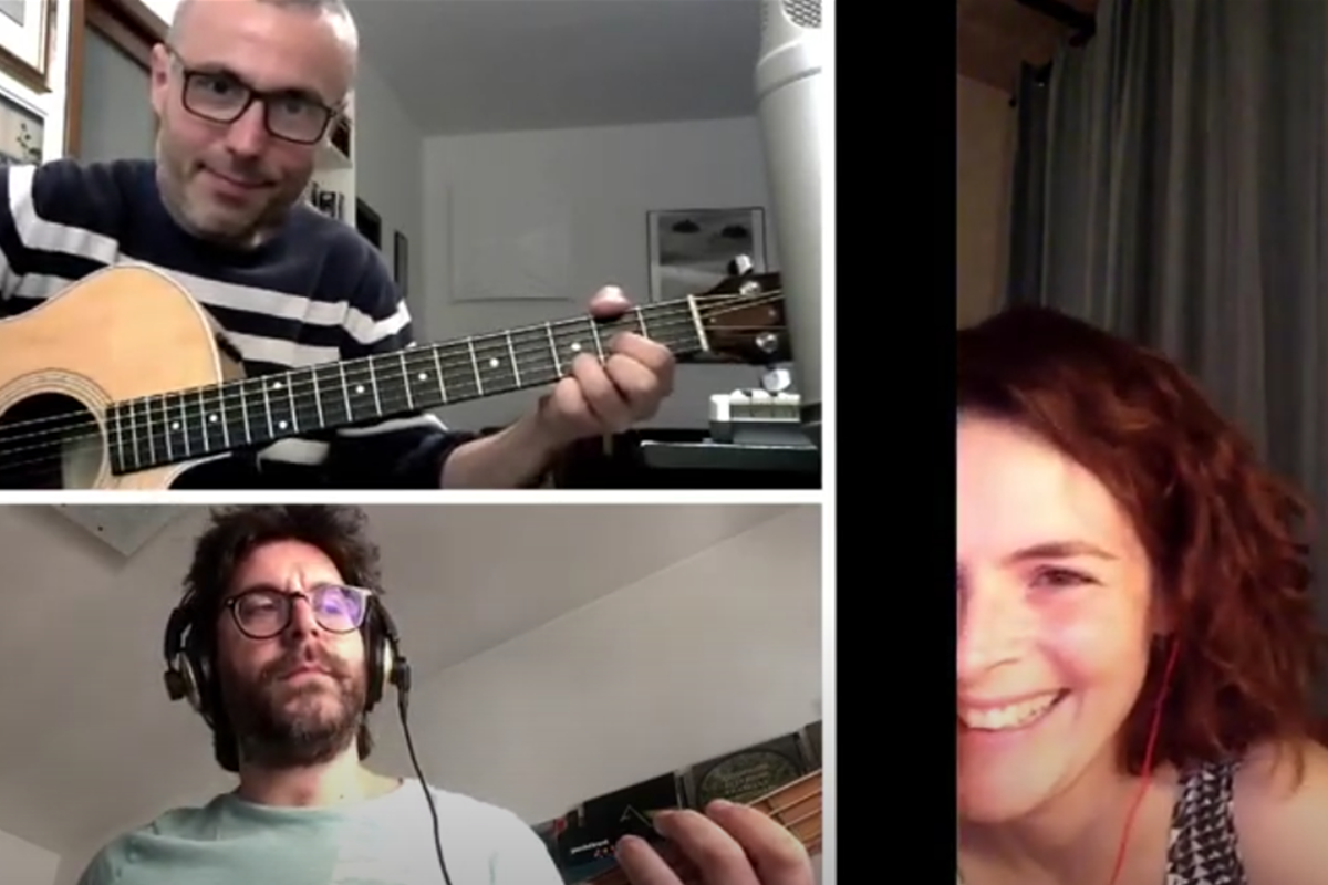 Two people playing guitars while another person smiles
