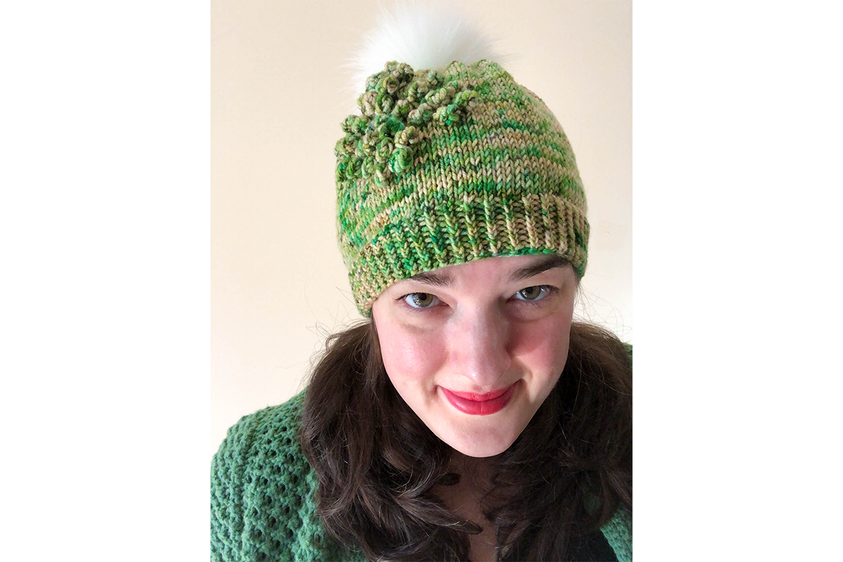 A smiling woman wearing a green knitted cap