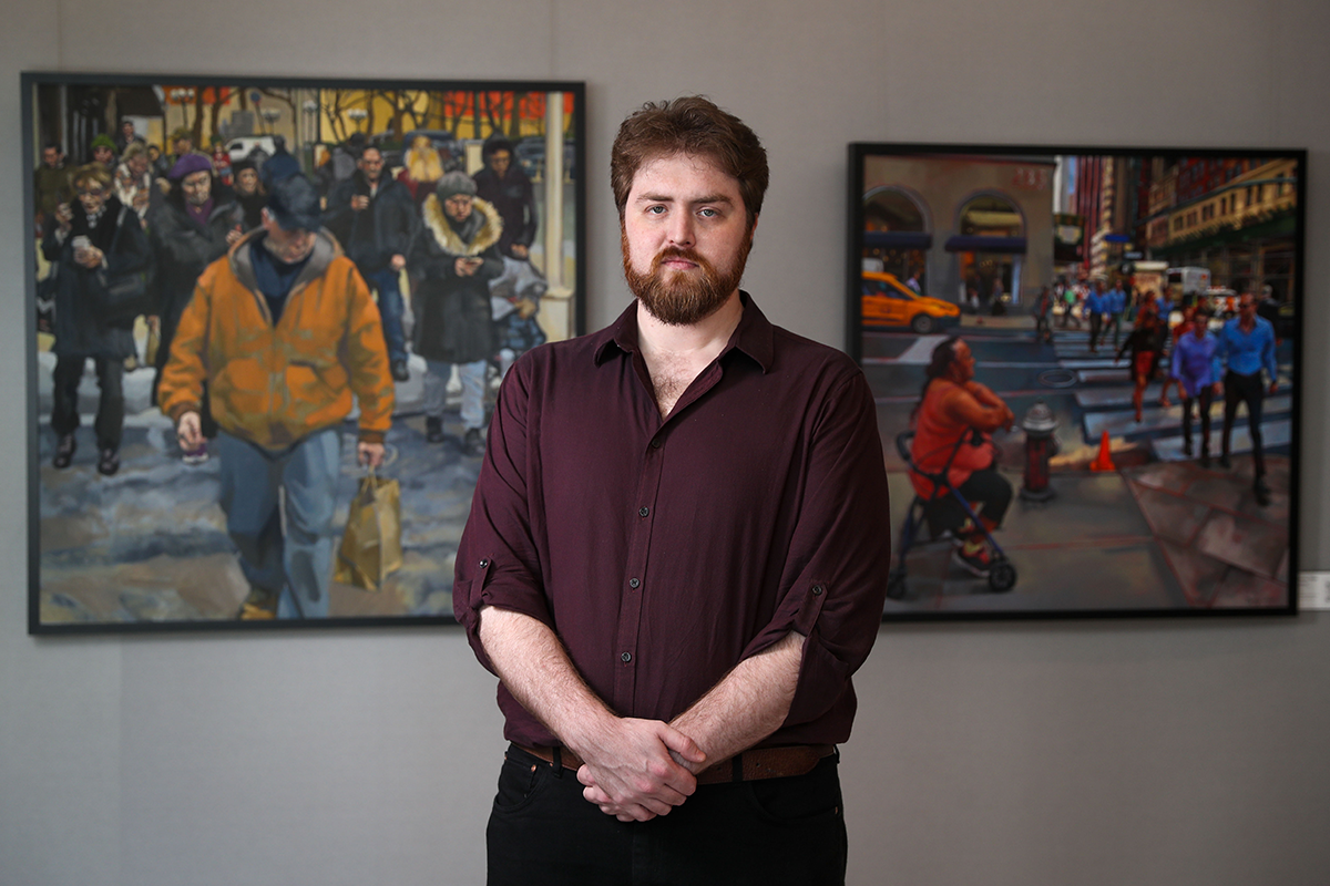 Danny Glass standing in front of two of his paintings