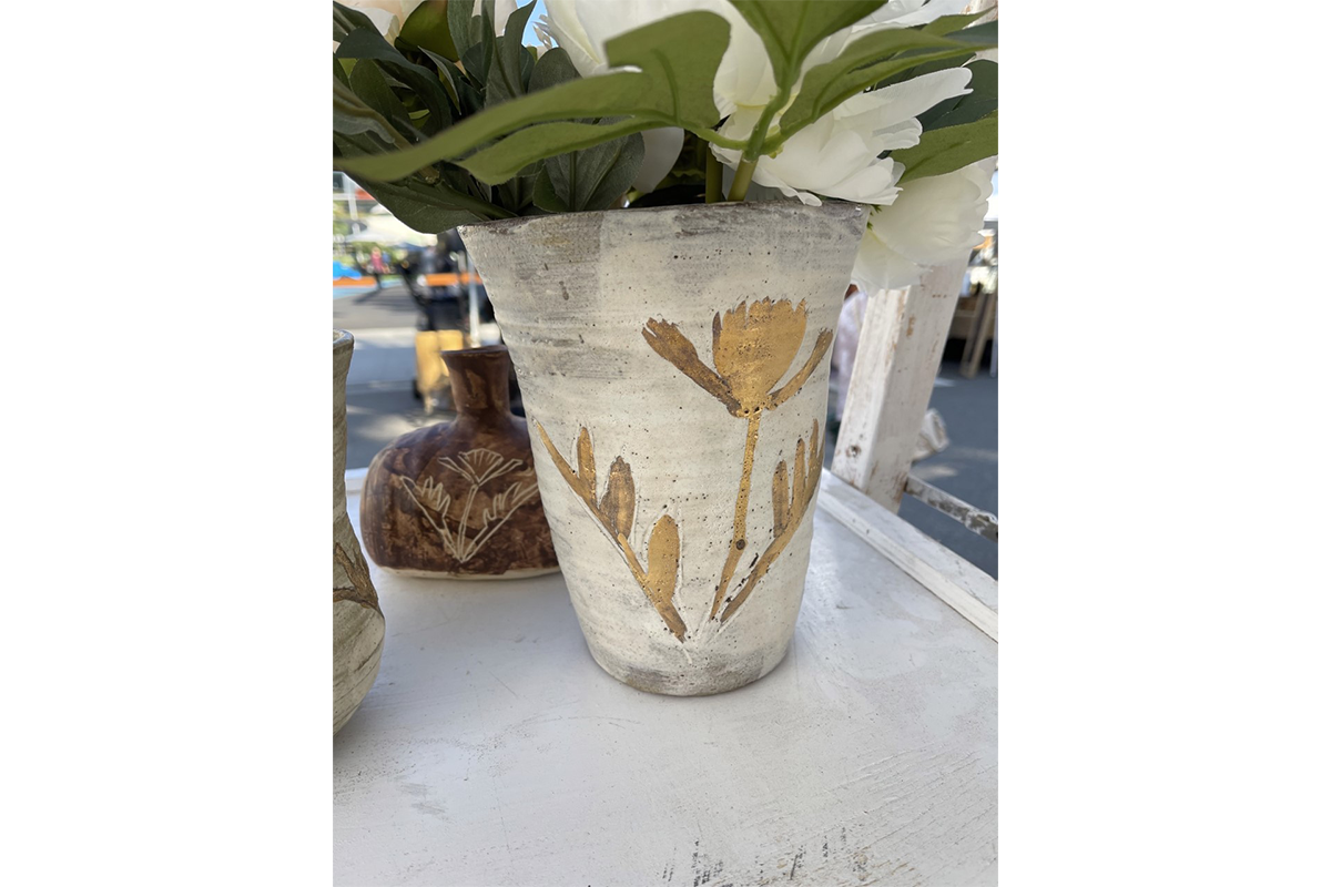 A white vase decorated with a gold California poppy