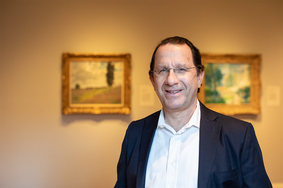 Image of a male standing in a RISD museum gallery wearing a white shirt and jacket