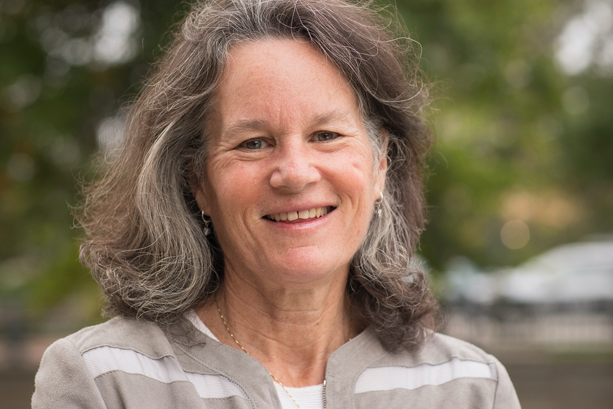 Image of a woman with grey hair wearing a grey and white striped cardigan