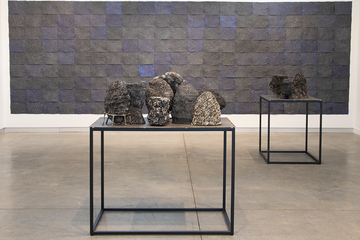 A gallery view of stone-like sculptures standing upright on a table