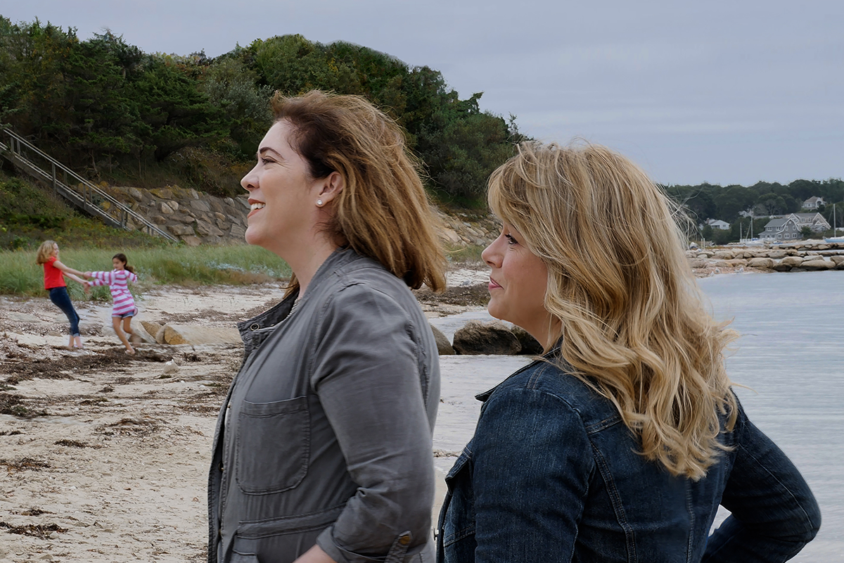 Two women looking at something off-camera and standing on a beach