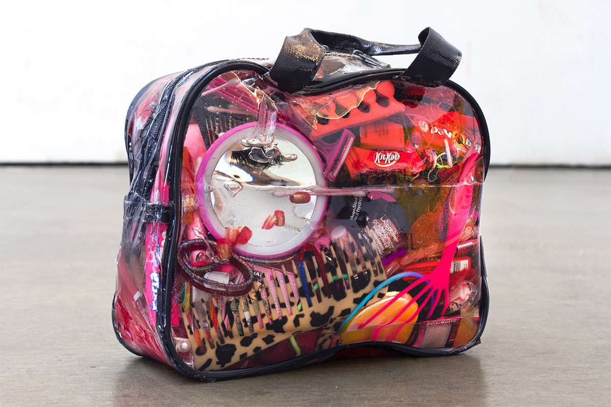 A clear bag filled with red and pink objects like candy and hair care products
