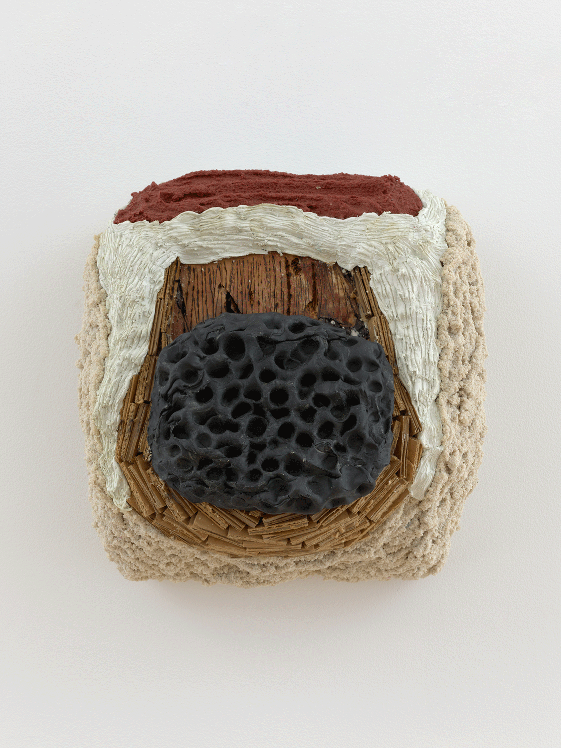 A sculpture of a black hive surrounded by various tan and beige pieces