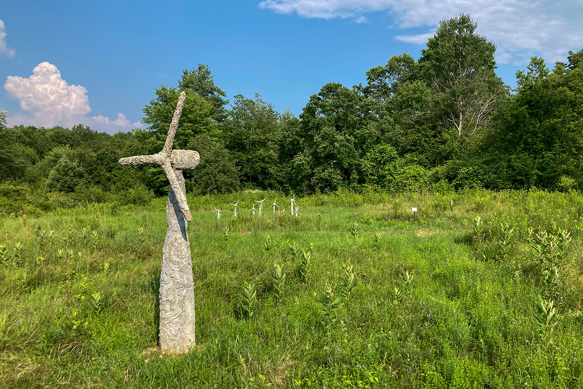 A concrete windmill in a field, with other concrete windmills in the distance